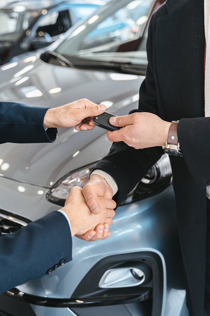 Close-up of a business handshake as car keys are handed over, symbolizing a new car purchase.
